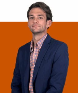 A man in a navy blazer and plaid shirt poses against a split black and orange background, embodying DANIEL WESLEY style.